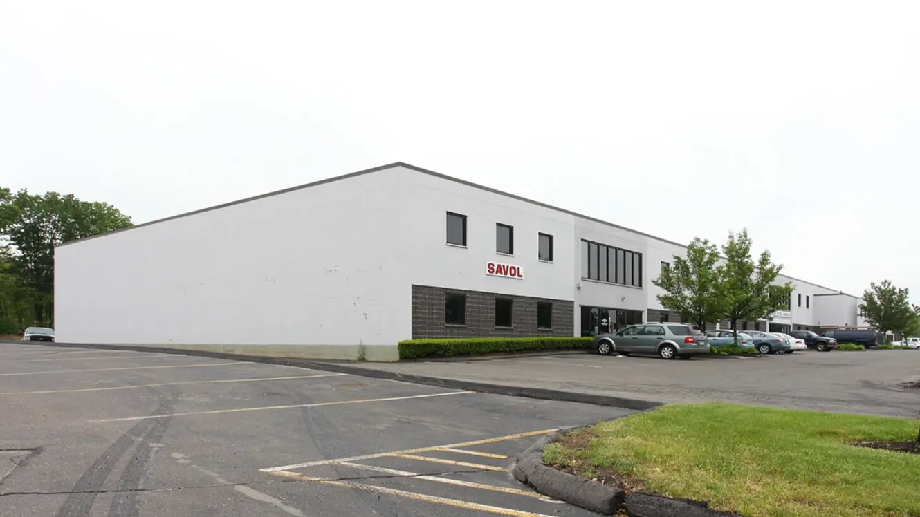 Exterior view of a Prestige Park industrial building in East Hartford, Connecticut, featuring white warehouse and flex-industrial space with adjacent parking.